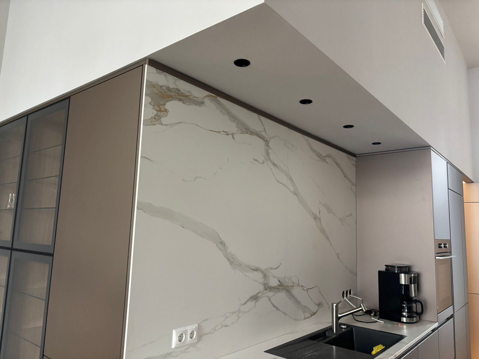 Moderne Küche mit Keramik-Rückwand in Marmoroptik und Einbauleuchten